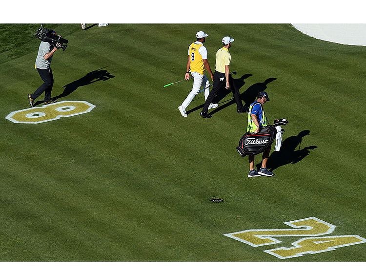  Tony Finau wears the jersey of Kobe Bryant while walking alongside Webb Simpson past a memorial on the fairway of the 16th during the final round of the Waste Management Phoenix Open golf tournament at TPC Scottsdale.