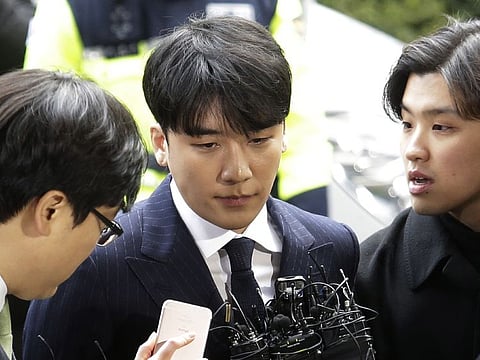 In this March 14, 2019, file photo, Seungri, center, member of a popular K-pop boy band Big Bang, arrives at the Seoul Metropolitan Police Agency in Seoul, South Korea.