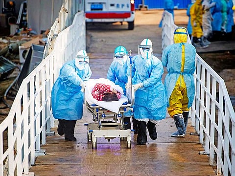 In this photo released by China's Xinhua News Agency, medical workers in protective suits help transfer the first group of patients into the newly-completed Huoshenshan temporary field hospital in Wuhan in central China's Hubei province. 