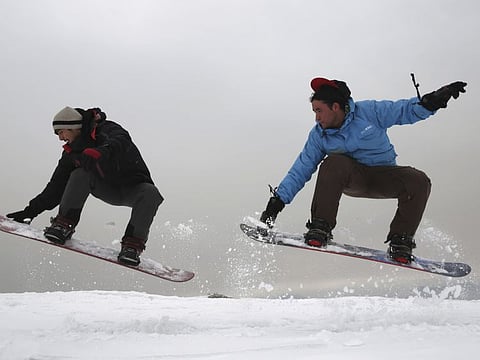 Ahmad Sorush, 22, left, and Nizaruddin Alizada, 20, make a jump on the snow-covered hillside known as Kohe Koregh, on the outskirts of Kabul, Afghanistan. 