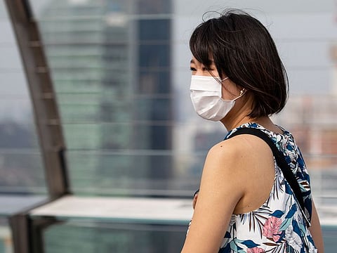 A woman wearing a protective mask walks on the observation deck of Marina Bay Sands hotel and casino in Singapore. 