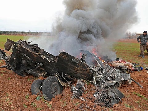 Syrian rebels gather around the alleged burning remains of a Syrian military helicopter after it was shot down over the village of Qaminas, near Idlib city in northwestern Syria on February 11. 