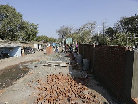 Indian workers construct a wall in front of a slum ahead of US President Donald Trump's visit, in Ahmadabad, India, Thursday.