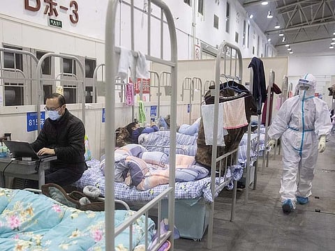 This photo taken on February 17, 2020 shows a man (L) who has displayed mild symptoms of the COVID-19 coronavirus using a laptop at an exhibition centre converted into a hospital in Wuhan in China's central Hubei province. 