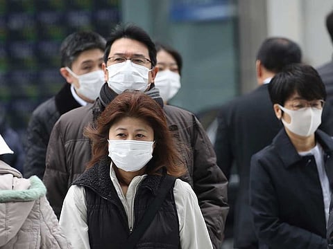 People wearing protective face masks cross a street in Tokyo.