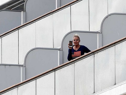 A passenger holds up her mobile phone while standing on the balcony of her cabin on the cruise ship Diamond Princess, where dozens of passengers were tested positive for coronavirus, at Daikoku Pier Cruise Terminal in Yokohama, south of Tokyo, Japan February 10, 2020. 