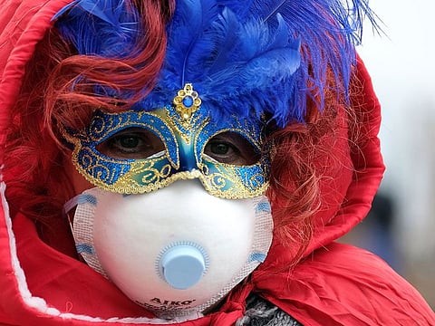 Masked carnival reveller wears protective face mask at Venice Carnival, which the last two days of, as well as Sunday night's festivities, have been cancelled because of an outbreak of coronavirus, in Venice, Italy February 23, 2020.  