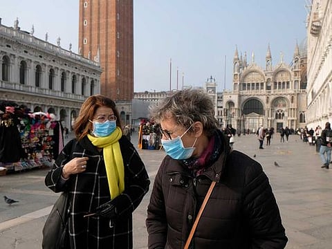 People wear protective face masks as they walk in St. Mark's Square after the last days of Venice Carnival were cancelled due to coronavirus, in Venice, Italy