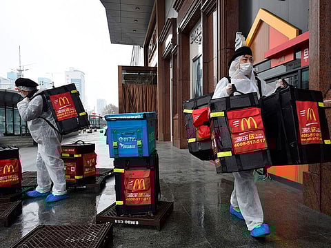 McDonalds workers wear protective suits as a preventive measure against the COVID-19 coronavirus as they prepare to deliver food to residents in Wuhan, in China's central Hubei province on February 26, 2020.