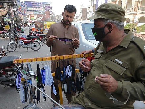 Residents buy protective facemasks as a prevention measure against the COVID-19 coronavirus alongside a street in Multan on February 27.