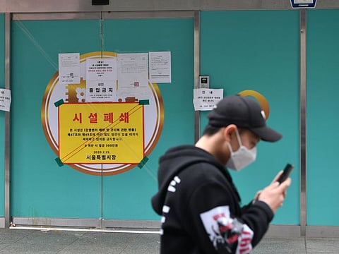 A man wearing a face mask walks past a branch of the Shincheonji Church of Jesus, which is temporarily closed by the government to help prevent the spread of the COVID-19 coronavirus, in Seoul on March 1, 2020. 