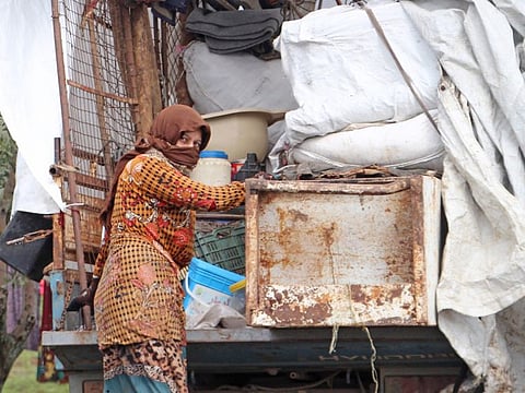 A displaced Syrian woman unloads a truck in Al Rouj plain on the outskirts of Syria's northwestern Idlib province on February 29. 