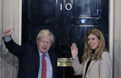 Britain's Prime Minister Boris Johnson and his partner Carrie Symonds wave from the steps of number 10 Downing Street in London on December 13, 2019.