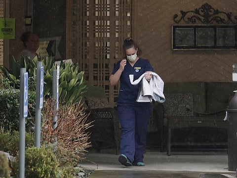 A worker at the Life Care Center in Kirkland, Washington state, near Seattle, wears a mask as she leaves the building, Monday, March 2, 2020.