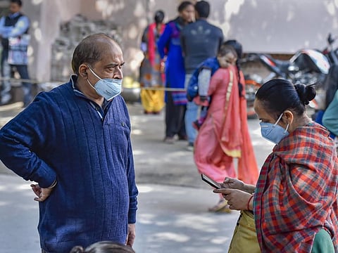 People wearing protective masks in the wake of the coronavirus outbreak, stand outside RML Hospital in New Delhi on Tuesday.