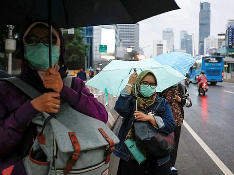 Women wearing protective masks stand at the sidewalk as they wait for a bus during rush hour, after Indonesia confirmed its first cases of COVID-19, in Jakarta, Indonesia.