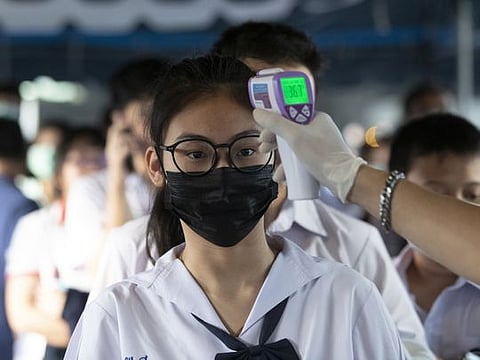 Health officials check students' temperatures before their exams, amid fears about the spread of the COVID-19, in Bangkok, Thailand