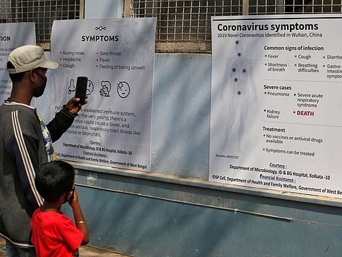 A man uses his mobile phone to take photographs of posters carrying messages on symptoms of coronavirus disease inside hospital premises in Kolkata on Thursday.