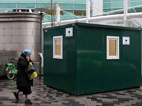 A pedestrian walks past an NHS 111 Coronavirus Pod, for people who believe they may be suffering from the virus, to attend and speak to doctors outside University College Hospital in London on March 5. 
