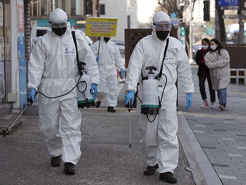 South Korean soldiers wearing protective gear spray disinfectant as a precaution against the new coronavirus on a street in Seoul, South Korea, on Friday.