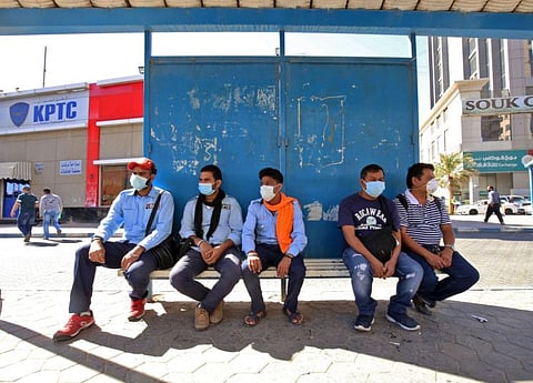 People wearing protective masks wait at a bus station in Kuwait City on March 2, amid a global outbreak of the novel coronavirus.