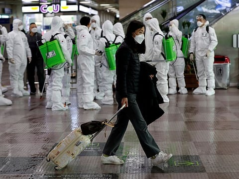 A traveller walks past South Korean soldiers who are mobilised for disinfection work at the international airport amid the rise in confirmed cases of coronavirus disease in Daegu, South Korea, on March 6, 2020.