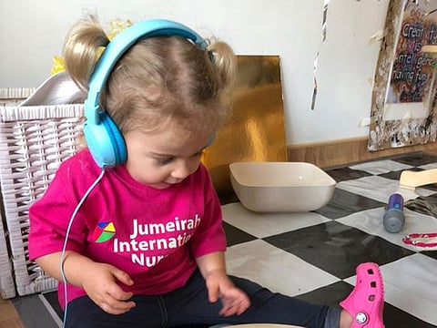 Two-year-old Luna of Jumeirah International Nursery (JIN) listens to an audio lesson shared to her by her teacher on an online learning platform