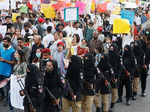 Female police officers escort women for a security measure as they attend the Aurat March (Women's March) in Karachi, Pakistan March 8, 2020.