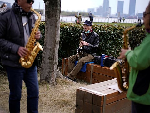 A man wears his face mask on his chin while he plays the saxophone at a park as the country is hit by an outbreak of the novel coronavirus COVID-19, in Shanghai, China March 8, 2020. 