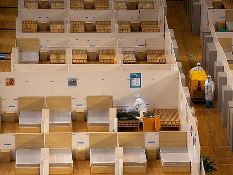 Workers in protective suits remove bed linen inside a closed makeshift hospital which had been converted from a sports stadium, following its last group of patients with coronavirus have been discharged, in Wuhan