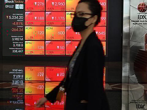A woman walks past a large screen showing the trading numbers on the Indonesia Stock Exchange (IDX) in Jakarta on March 9, 2020. Equity markets collapsed on March 9 as the rapidly spreading coronavirus fans fears for the global economy, while a crash in oil prices added to the panic with energy firms taking a hammering and wiping hundreds of billions off valuations.