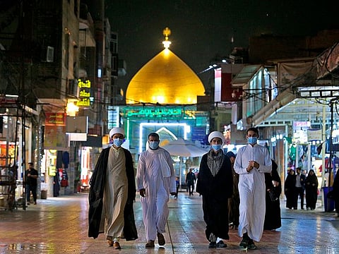 Shiite pilgrims walk outside the shrine of Imam Ali in Najaf, Iraq