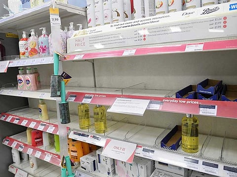 A sign, on empty shelves, alerting customers to limited sales of antibacterial hand washes and sanitiser gels, inside a Boots store in London.
