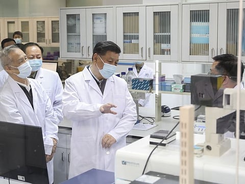 Chinese President Xi Jinping, centre, wearing a protective face mask, talks to a medical staff member during his visit to the Academy of Military Medical Sciences in Beijing