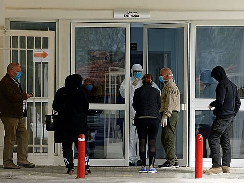 People wear face masks as they stand at the entrance of Rafik Hariri hospital, as Lebanon recorded its first death from coronavirus, in Beirut