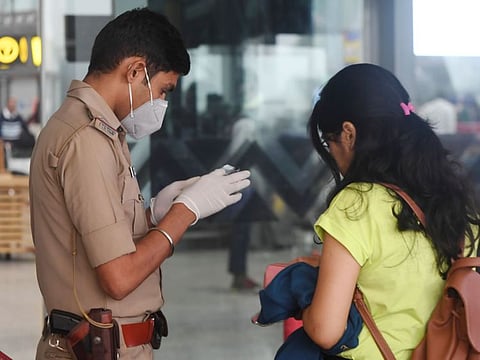 India's Central Industrial Security Force (CISF) personnel wearing a facemask as a preventive measure against the spread of coronavirus checks the details of a passenger at Netaji Subhas Chandra Bose International Airport in Kolkata on March 7, 2020.