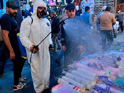 A civil defense worker wearing a protective suit sprays disinfectant as a precaution against the new coronavirus, in the main market, Baghdad, Iraq, Tuesday, March 10, 2020. For most people, the new coronavirus causes only mild or moderate symptoms, such as fever and cough. For some, especially older adults and people with existing health problems, it can cause more severe illness, including pneumonia.