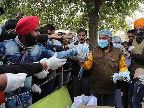 A volunteer distributes face masks for prevention against Covid-19 outside a government run hospital in Jammu, India, on Thursday.