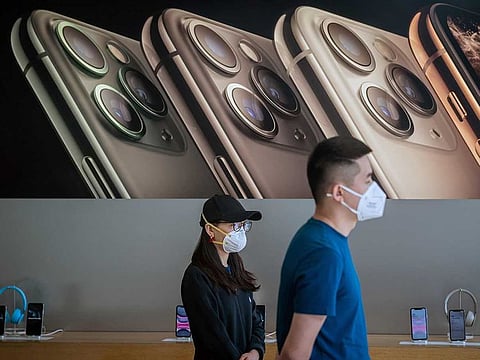 In this picture taken on March 11, 2020 Apple staff wearing face masks as a preventive measure against the COVID-19 coronavirus wait for customers at an Apple shop in Beijing.