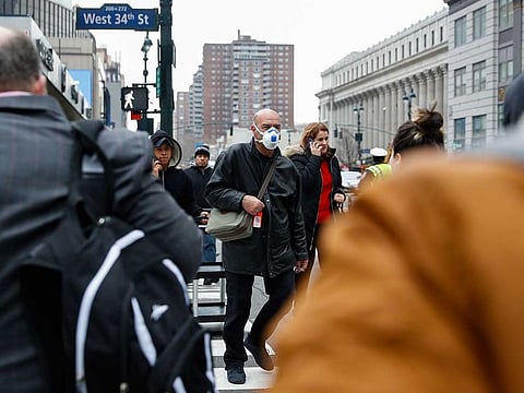 A pedestrian wears a face mask while crossing West 34th Street in New York on Thursday, March 12, 2020. 
