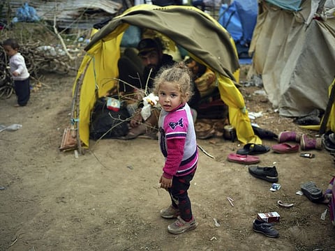 A child walks next to tends in a migrant camp set up near the Turkish-Greek border in Pazarkule, Edirne region, Turkey, Tuesday, March 10, 2020.