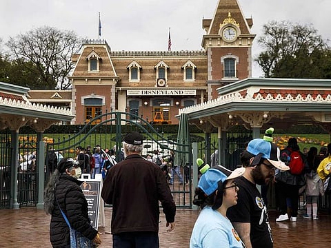 Guests enter Walt Disney Co.'s Disneyland theme park in Anaheim, California, U.S., on Friday, March 13, 2020. Fans in Orlando, Florida, and Anaheim, California, lined up Friday morning to visit Walt Disney Co.s theme parks before they close due to the coronavirus. 