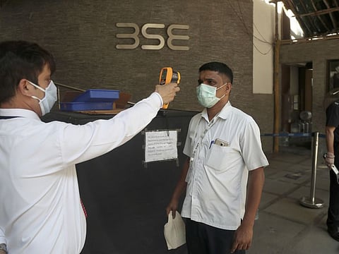 A security official checks the temperature of a visitor at the Bombay Stock Exchange (BSE) building in Mumbai on Monday, March 16, 2020.