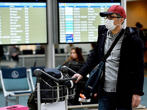 A traveller wearing a protective mask walks through Vancouver International Aiport (YVR) in Vancouver, British Columbia, Canada, on Tuesday, March 17, 2020.