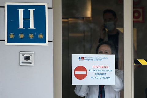 A health worker hangs a placard reading "Restricted entry" on the entrance door of the Gran hotel Colon in Madrid, the first hotel that was transformed into a medical facility to treat the least serious cases amid the outbreak caused by the novel coronavirus, on March 19, 2020.