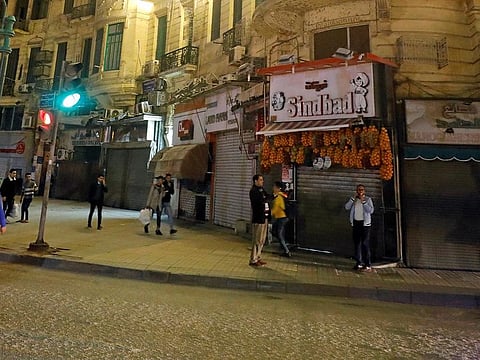 People walk in front of closed shops, after Egyptian Prime Minister Mostafa Madbouly ordered all restaurants, cafes, cafeterias, night clubs, shopping malls and shops to shut their doors from 7pm due to the coronavirus disease (COVID-19) outbreak in Cairo.