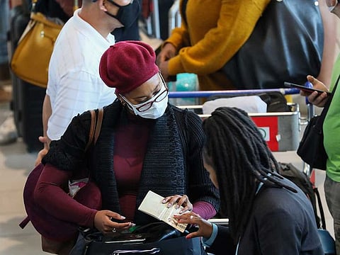 A passenger has her passport checked while waiting in line to check in for a flight at Cape Town International Airport, amid the coronavirus outbreak, in Cape Town, South Africa, on March 18, 2020. 