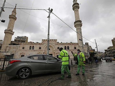 Greater Amman Municipality employees sanitize cars on the street amid concerns over the coronavirus (COVID-19) spread, outside Al Husseini Mosque in downtown Amman, Jordan, March 20, 2020. 
