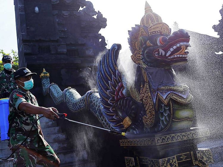 Indonesian soldiers spray disinfectant on a statue to prevent the spread of coronavirus disease (COVID-19) at Tanah Lot temple in Tabanan, Bali, Indonesia, March 20, 2020. 