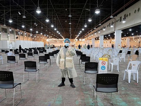 A volunteer who directs visitors at a coronavirus testing centre, gestures at the Kuwait International Fairgrounds in Mishref, Kuwait on March 18.